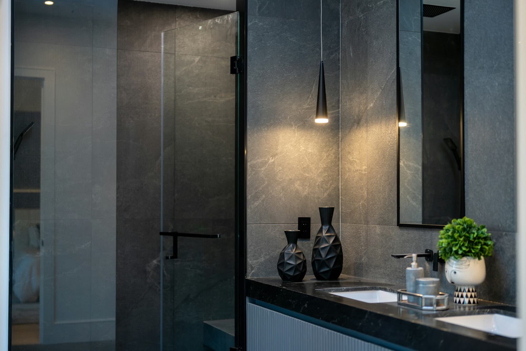Moody bathroom in dark stone with brass pendant lights