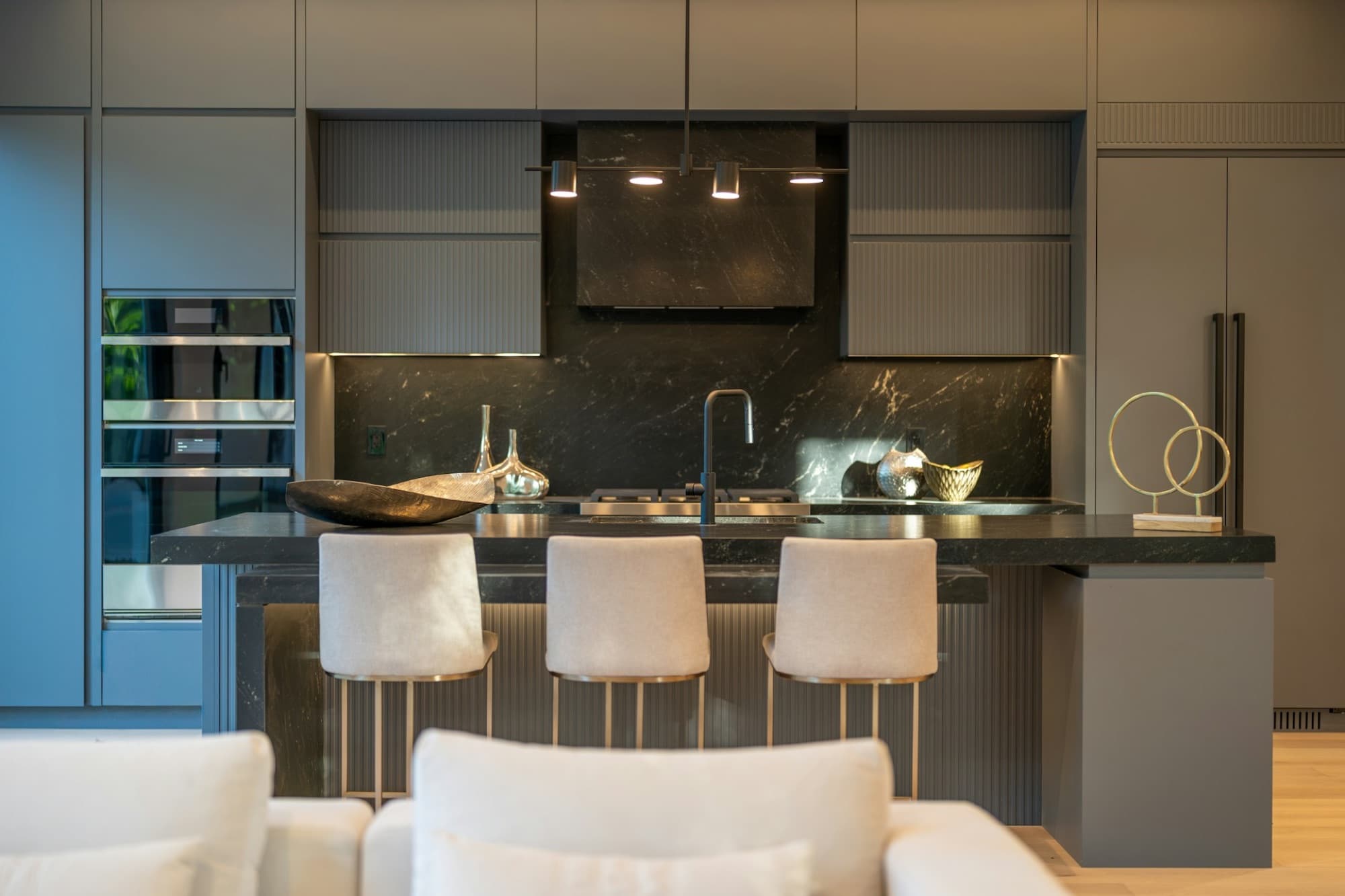 Charcoal kitchen with black marble splashback and cream bar stools